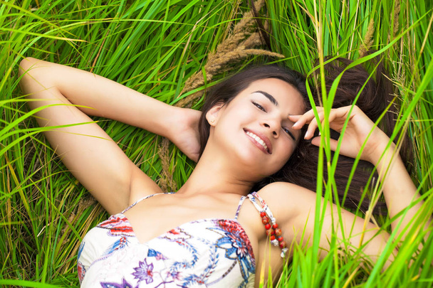 Happy woman resting and day lying down on green grass - Photo, Image