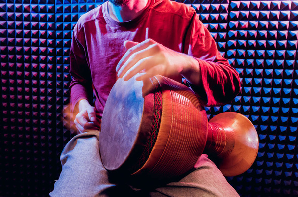 Young man playing on djembe in sound recording studio. African drums - Fotó, kép