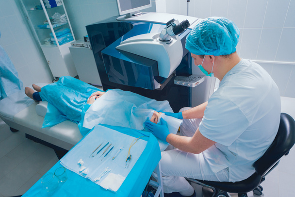 paciente e equipe de cirurgiões em centro cirúrgico durante cirurgia oftálmica
 - Foto, Imagem
