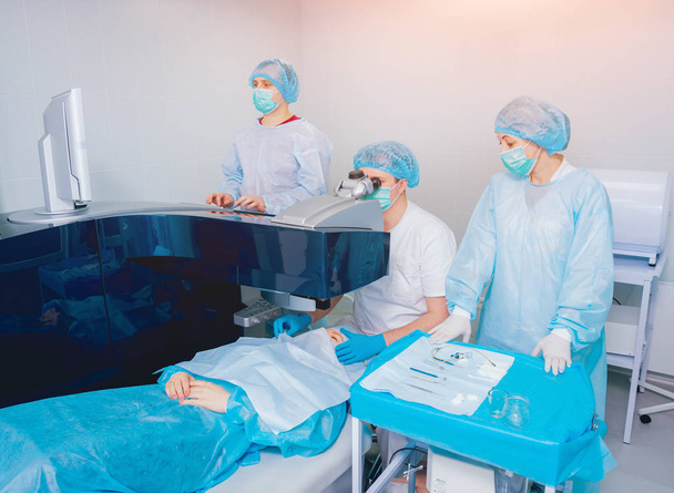 patient and team of surgeons in operating room during ophthalmic surgery - Φωτογραφία, εικόνα