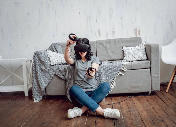 Young girl playing games with virtual reality goggles at home. VR technologies - Foto, Imagem