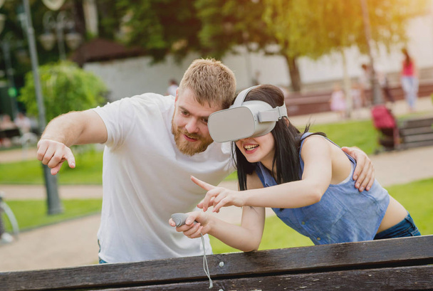 Joven pareja caucásica juega un juego con gafas de realidad virtual en la calle. Auriculares VR
. - Foto, imagen