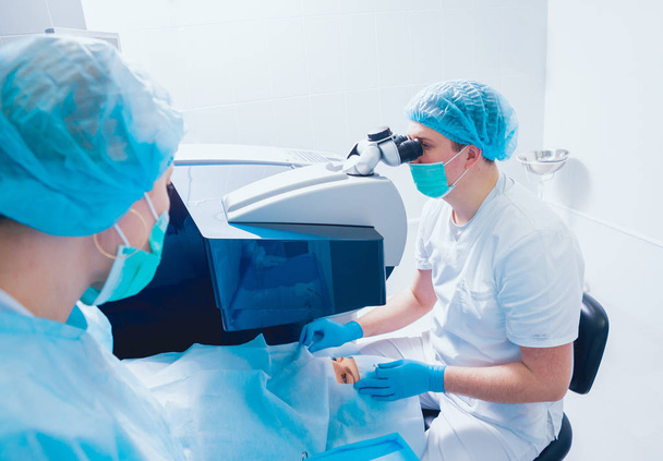 patient and team of surgeons in operating room during ophthalmic surgery - Photo, image