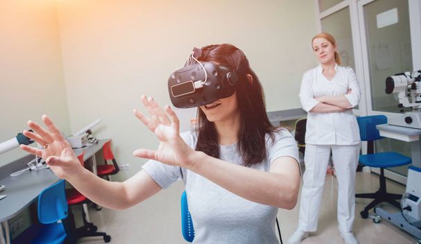 Ophthalmology doctor checking girl vision with help of virtual reality goggles - Foto, Imagen