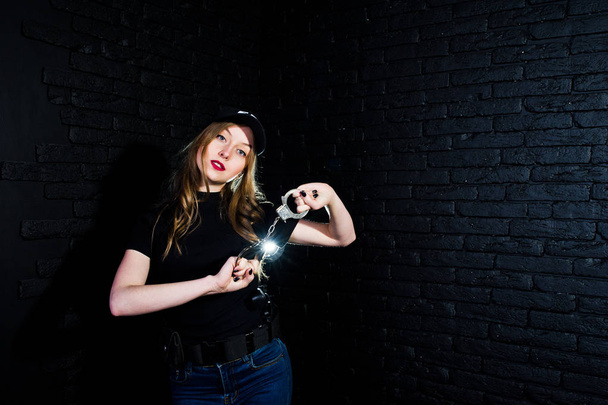 FBI female agent in cap and with gun at studio against dark brick wall. - Foto, immagini