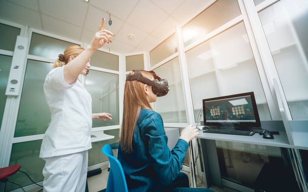 Oftalmología médico comprobar la visión de la niña con la ayuda de gafas de realidad virtual
 - Foto, Imagen