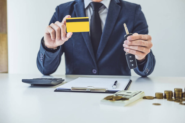 Salesman holding a key, credit card and calculating a price of selling new car and home loan, transportation and ownership concept. - Fotoğraf, Görsel