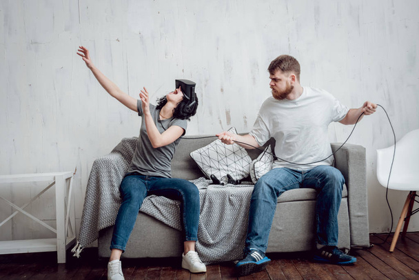 Young man with girlfriend playing games with virtual reality goggles at home. VR technologies - Fotó, kép