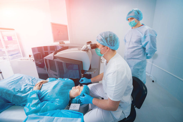 patient and team of surgeons in operating room during ophthalmic surgery - Foto, immagini