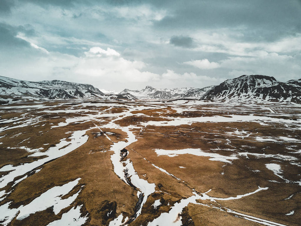 Iceland aerial view Landscape with snow and clouds, street and yellow and green grass - 写真・画像