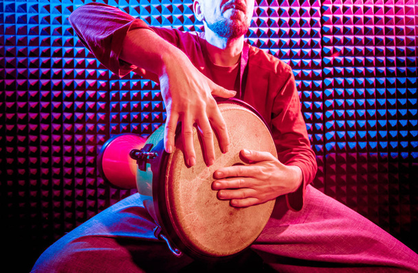Young man playing on djembe in sound recording studio. African drums - Fotoğraf, Görsel
