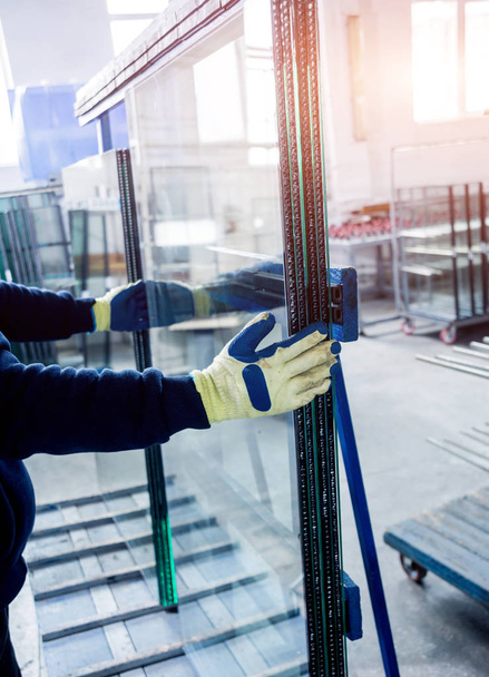 I lavoratori trasferiscono il vetro. In fabbrica per la produzione di finestre e porte in alluminio e PVC
 - Foto, immagini