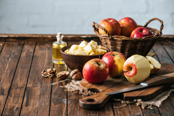 vista de cerca de la botella de jugo, manzanas frescas en la tabla de cortar, avellanas y cuchillo en la superficie de madera
 - Foto, Imagen