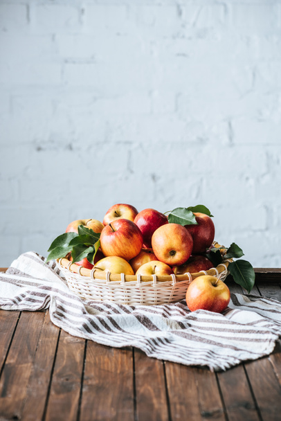 close up view of apples in basket on linen on dark wooden surface - Fotoğraf, Görsel