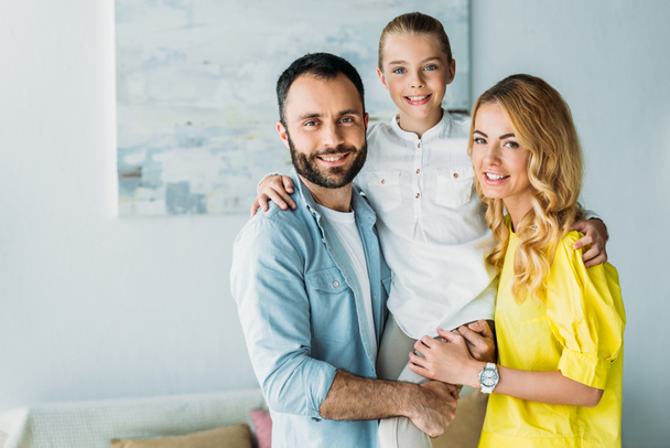 happy young family standing together at home and looking at camera - Zdjęcie, obraz