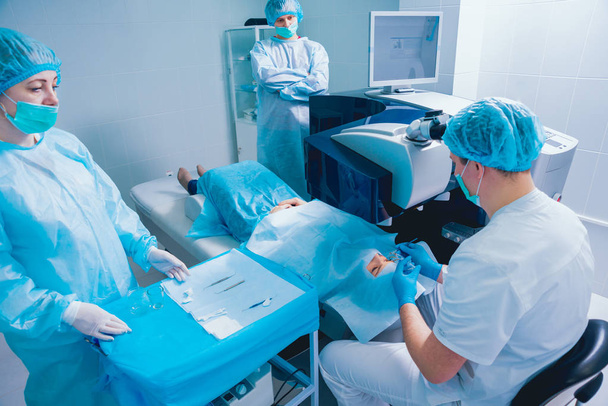 patient and team of surgeons in operating room during ophthalmic surgery - Фото, зображення