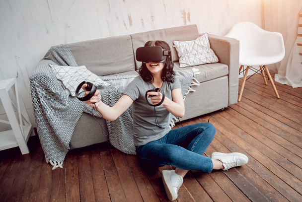 Young girl playing games with virtual reality goggles at home. VR technologies - 写真・画像
