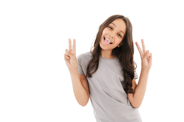Image of pretty cute girl standing isolated over white wall background. Looking camera make peace gesture. - 写真・画像