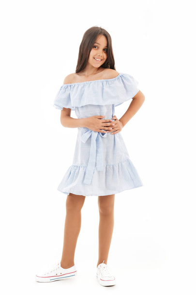 Full length image of Smiling young brunette girl in dress posing with arm on hip and looking at the camera over white background - Foto, Imagen