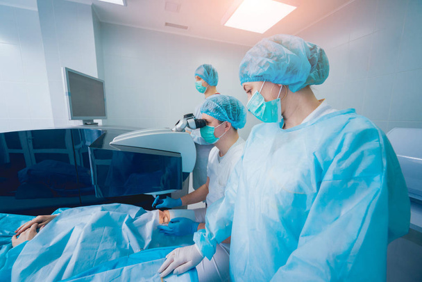patient and team of surgeons in operating room during ophthalmic surgery - Foto, immagini