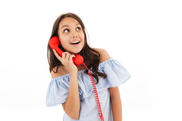 Photo of pretty cute girl standing isolated over white wall background looking aside talking by telephone. - Фото, изображение