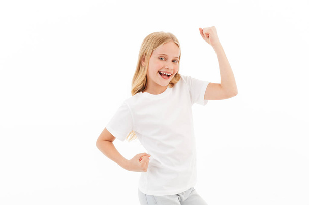 Happy young blonde girl in casual clothes rejoices while looking at the camera over white background - Photo, image