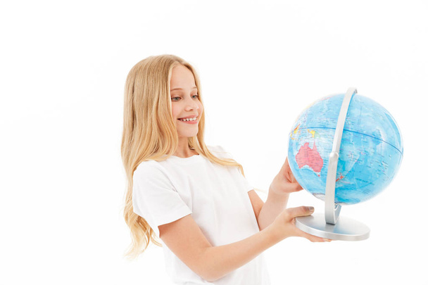 Picture of Smiling young blonde girl in casual clothes holding globe over white background - Zdjęcie, obraz