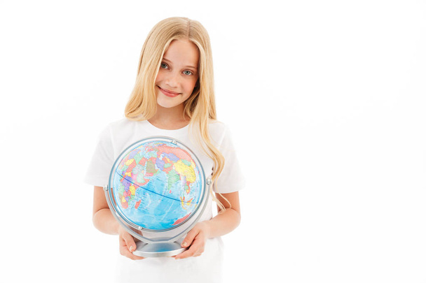 Happy young blonde girl in casual clothes holding globe and looking at the camera over white background - Foto, Imagen