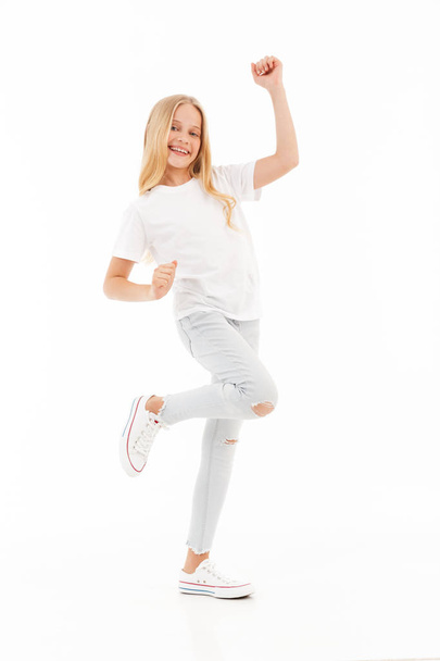 Full length image of Cheerful young blonde girl in casual clothes rejoices and looking at the camera over white background - Foto, Bild