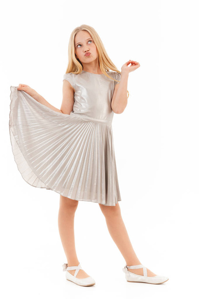 Full length image of Carefree young blonde girl in dress posing and looking up over white background - Foto, imagen
