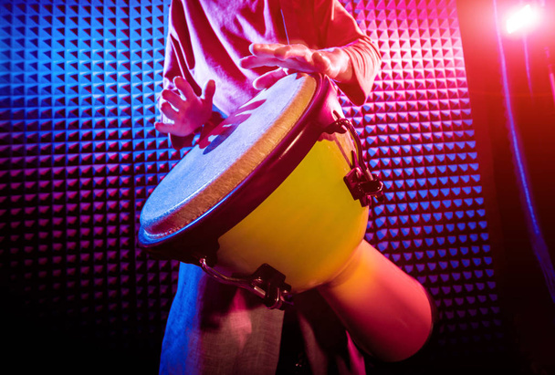Young man playing on djembe in sound recording studio. African drums - Foto, Imagen
