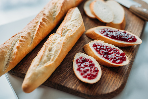 close-up shot of sliced baguette with jam on wooden cutting board - Фото, зображення
