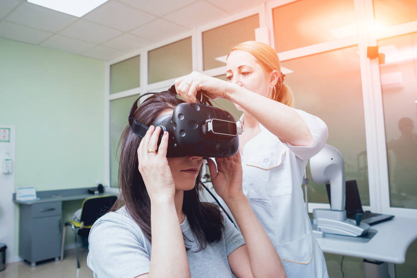 Ophthalmology doctor checking girl vision with help of virtual reality goggles - Valokuva, kuva
