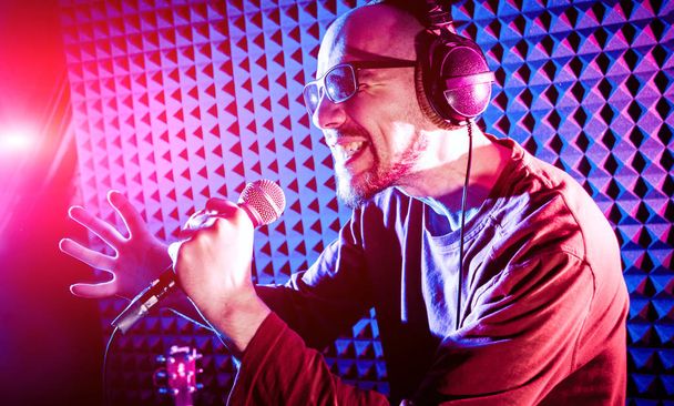 The singer sings with a microphone in the recording studio. Modern background - Φωτογραφία, εικόνα