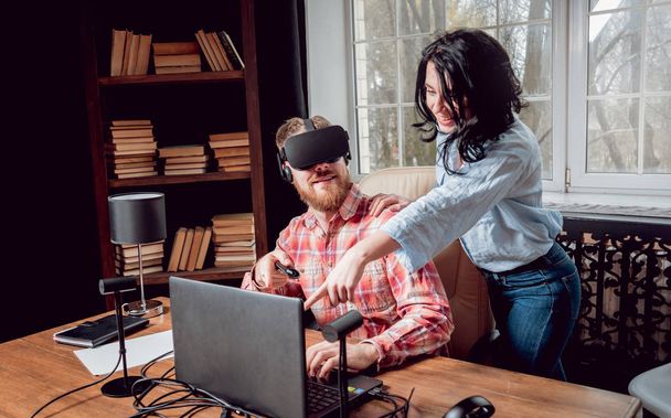 Young man and girl plays a game with virtual reality goggles at cabinet room.  - Fotó, kép