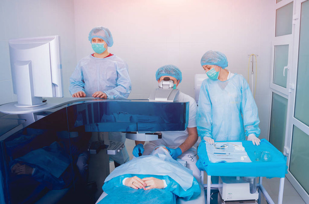 patient and team of surgeons in operating room during ophthalmic surgery - Valokuva, kuva