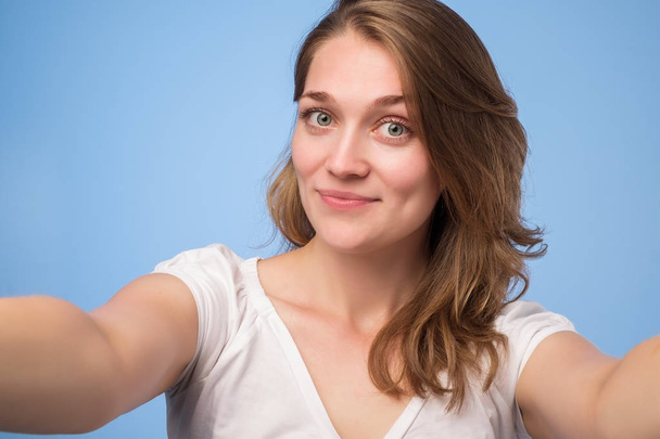 Close-up de jovem europeia bela mulher tomando selfie. Isolado em fundo azul
 - Foto, Imagem
