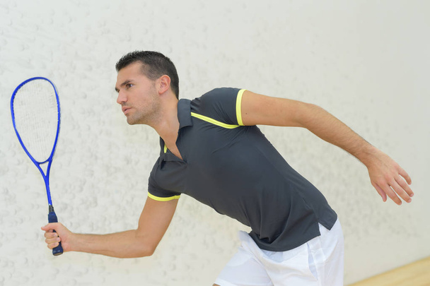 young man playing tennis indoors - Фото, изображение