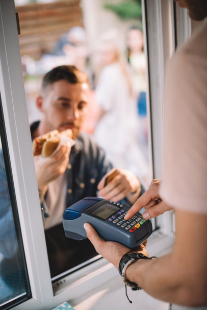 επιλεκτική εστίαση του πελάτη που πληρώνουν για χοτ-ντογκ σε φορτηγό τροφίμων - Φωτογραφία, εικόνα