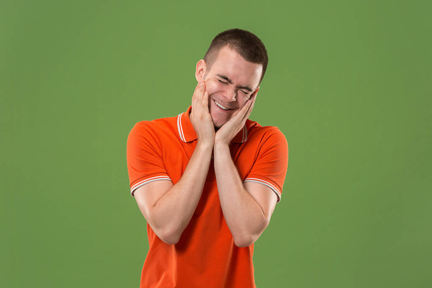 Beautiful male half-length portrait isolated on green studio backgroud. The young emotional surprised man - Photo, Image