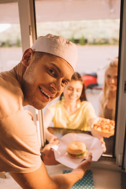 chef souriant donnant hamburger et frites aux clients de camion alimentaire
  - Photo, image