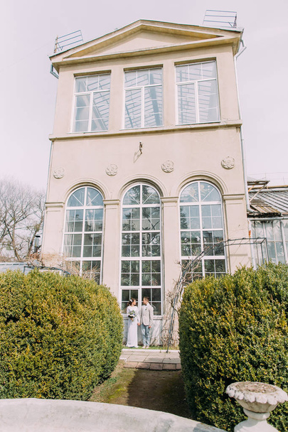 Stylish young couple near the old beige house with columns and big vintage windows. Romantic wedding in Paris - Photo, image