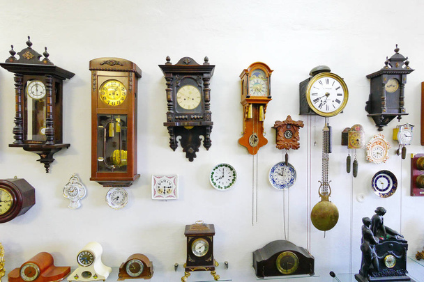 The museum exposition of watches of different sizes, material and gear against a white wall - Valokuva, kuva