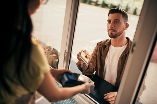 imagen recortada de un cliente guapo que paga con tarjeta de crédito por comida en camión de comida
 - Foto, Imagen