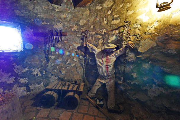 Sala de tortura del museo con una imagen de un hombre encadenado sobre un fondo de pared de piedra
 - Foto, Imagen
