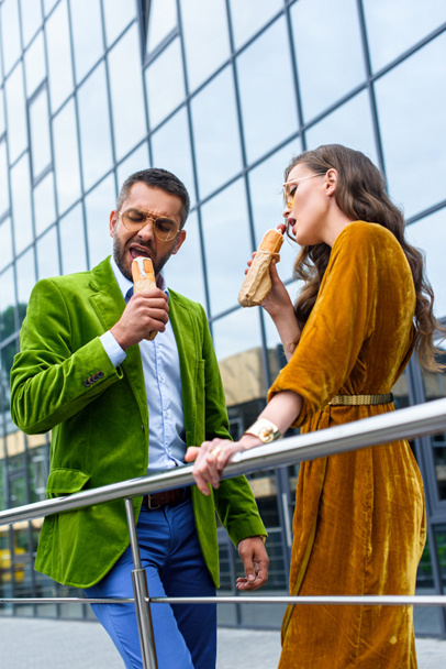 couple in luxury outfit eating french hot dogs on street - Foto, Imagem