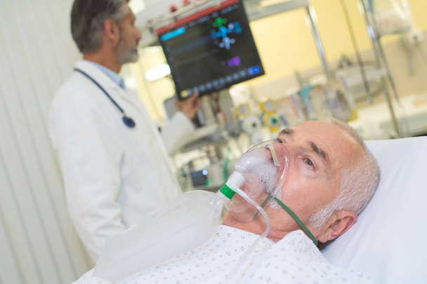doctor examining his patient wearing oxygen mask - Fotografie, Obrázek