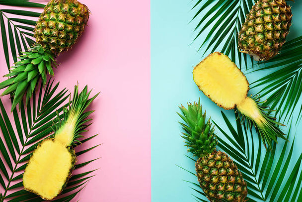 Pineapples, palm leaves on pastel colorful pink and turquoise background with copy space. Creative summer concept. Flat lat, top view - Foto, immagini