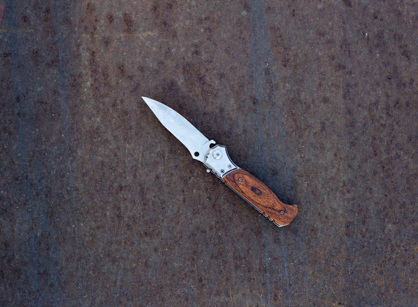Folding knife on rusty metal background, close up - Photo, Image
