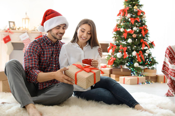 Young couple with Christmas gift at home - Foto, Imagen